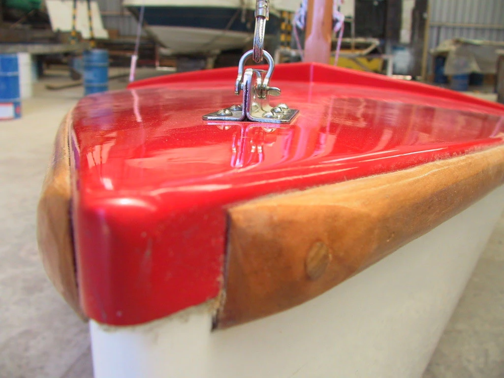 Detalle de herraje de proa sobre cubierta roja con canto de madera